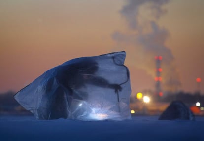 Un hombre cubierto con una bolsa de plástico para protegerse contra el viento y el frío, pesca a través de un agujero abierto en el hielo, en el Golfo de Finlandia, al oeste de San Petersburgo, Rusia.