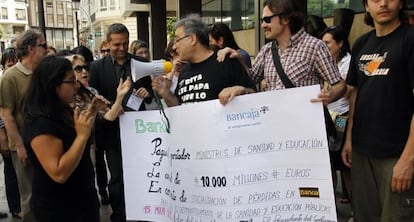 Los participantes de la 'Ruta por el despilfarro valenciano' entregan un cheque en la sede de Bankia de Valencia.