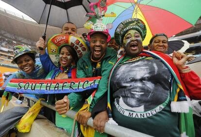 Varios sudafricanos cantan y bailan bajo la lluvia mientras ocupan el estadio FNB de Soweto para asistir al servicio religioso oficial en memoria del expresidente Nelson Mandela en Johannesburgo, Sudáfrica.