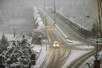 Dos vehículos circulan por una calle de Teruel bajo una intensa nevada.
