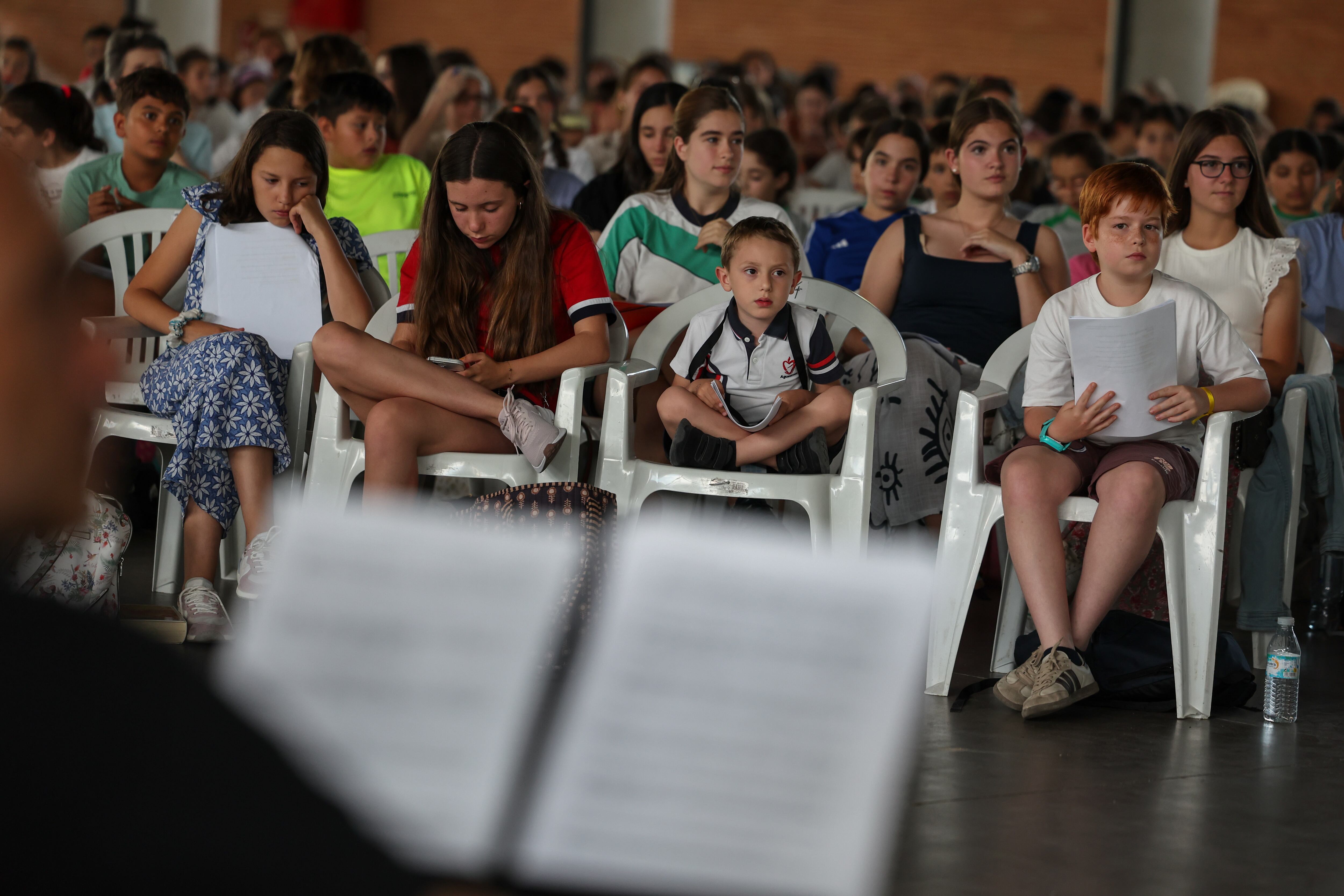 Un grupo de niños presta atención a las indicaciones del director del coro.
