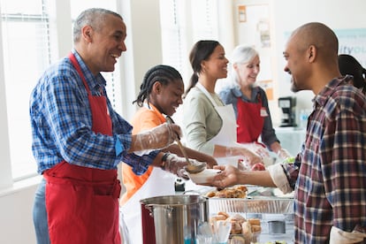 Voluntarios sirviendo comida en cocina comunitaria.