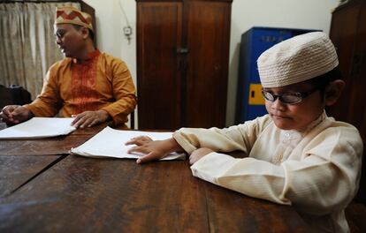 Un niño y un adulto, durante una clase de lectura del Corán en braille.