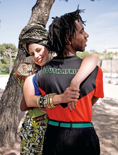 A la izquierda, Madeline, con 'total look' de inspiración africana de Juanjo Oliva, pulseras y anillo de El Templo de Susu, abraza a Carlos. Él lleva camiseta de la selección de Sudáfrica de Adidas, pantalón de Dolce & Galbana y cinturón de Justo Arroyo.