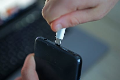 Una persona conecta un cargador USB de tipo C en un dispositivo mvil. 