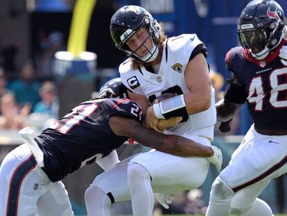 Jacksonville Jaguars quarterback Trevor Lawrence, center, is hit by Houston Texans cornerback Steven Nelson (21) on a run during the first half of an NFL football game, Sunday, Sept. 24, 2023, in Jacksonville, Fla.
