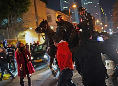 Agentes de policía a caballo tratan de impedir que los manifestantes corten el tráfico en una céntrica avenida de Tel Aviv en la noche del sábado delante de unas instalaciones militares.