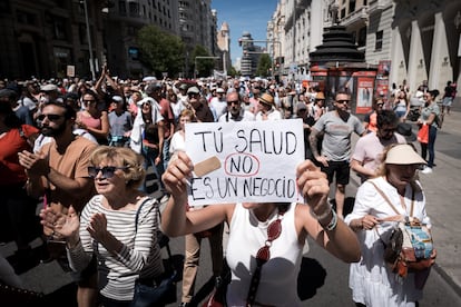 Un manifestante exhibe el lema "Tu salud no es un negocio" mientras avanza por la Gran Vía durante la marcha.