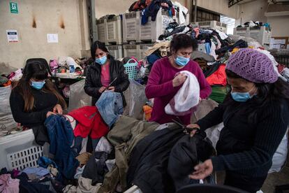 Trabajadores arrancan botones de metal para reutilizar ropa usada para hacer hilo ecológico en la fábrica de Ecocitex en Santiago, el 8 de octubre de 2021.