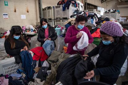 Trabajadores arrancan botones de metal para reutilizar ropa usada para hacer hilo ecológico en la fábrica de Ecocitex en Santiago, el 8 de octubre de 2021. 