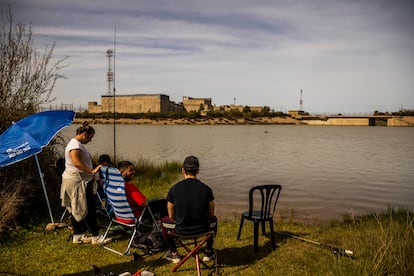 Varios jóvenes pescan con la central nuclear de Valdecaballeros de fondo. 
