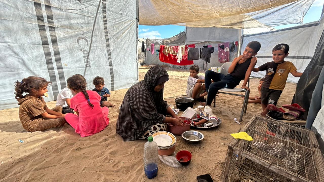 Huwaida Omran lava platos y cubiertos rodeada por sus nietos, en Al Mawasi, en el sur de Gaza, el 1 de octubre de 2025.