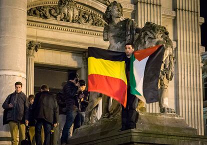 Un hombre sujeta una bandera belga y otra de siria durante un homenaje improvisado a las víctimas de los atentados en Bruselas en Bélgica, el 22 de marzo de 2016.