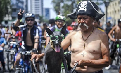 Un anciano posa junto con su mascota durante una marcha de ciclistas desnudos en Lima.