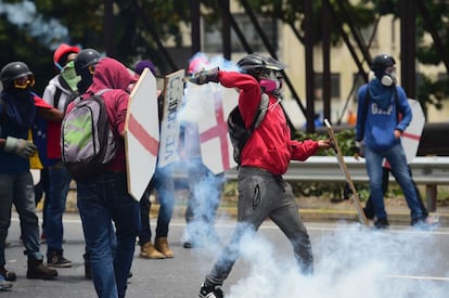 Un manifestante arroja un bote de humo a las fuerzas policiales durante las protestas en Caracas (Venezuela).