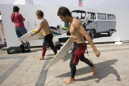 Dos surfistas pasan junto un mural que pinta un joven, ayer en la salida de la playa de Zarautz.