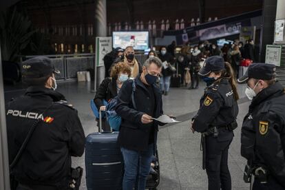 Agentes de la Policía Nacional piden la documentación a los viajeros en la estación del AVE de Atocha de Madrid. Desde este miércoles y hasta el 6 de enero la Comunidad de Madrid permanecerá cerrada para evitar la propagación del coronavirus durante las fiestas navideñas, por lo que están prohibidas las entradas y salidas de la región en este periodo salvo excepciones, como visitar a familiares o allegados.