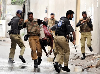 Agentes de la policía pakistaní llevan a uno de los fieles heridos en los asaltos a dos mezquitas en Lahore.