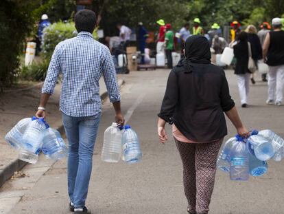 Dos personas acuden a llenar sus garrafas de agua en Ciudad del Cabo durante la crisis de 2018.