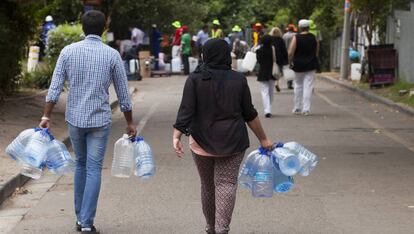 Dos personas acuden a llenar sus garrafas de agua en Ciudad del Cabo durante la crisis de 2018.