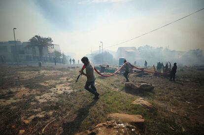 Residentes y bomberos voluntarios luchan por contener un incendio avivado por fuertes vientos en las laderas de la montaña de la Mesa en Ciudad del Cabo, Sudáfrica.