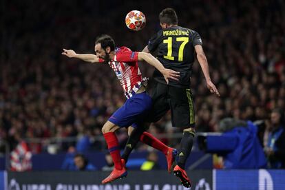 El defensa del Atlético, Juanfran, y el delantero de la Juventus, Mario Mandzukic, saltan para cabecear el balón.