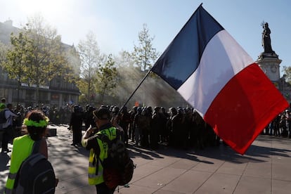 Un manifestante sostiene una bandera francesa mientras pasa junto a los policías antidisturbios en la Plaza de la Republiqua en París. Los enfrentamientos han sido continuos durante toda la jornada.