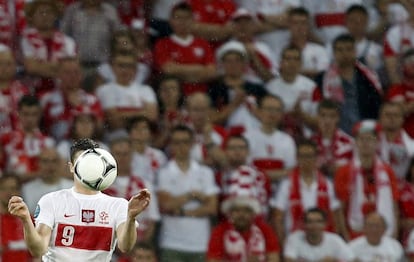 El polaco Robert Lewandowski cabecea un balón ante la mirada de los aficionados