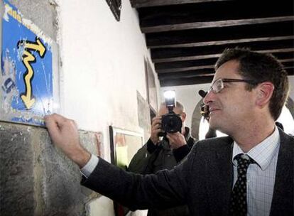 El presidente del PP vasco, Antonio Basagoiti, retira una pegatina de radicales en la puerta del Ayuntamiento de Lizartza. La pegatina dice "que se vayan"