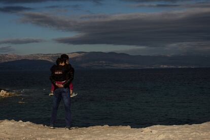 CESME, TURKEY - DECEMBER 03: An Afghan refugee holds his daughter as he looks out to Chios Island, Greece as they wait to leave turkey at a launching point in the coastal town of Cesme on December 3, 2015 in Cesme, Turkey. The flow of boats from Turkey has slowed after a 3bn euro deal was struck between the EU and Turkey, to slow the flow of migrants and refugees to Europe. Since the deal was on November 29th, Turkish police have rounded up approximately 1300 migrants and arrested a number of smugglers. Police checkpoints on the roads leading to launch points have been increased slowing the amount of boats leaving turkish shores.  (Photo by Chris McGrath/Getty Images)