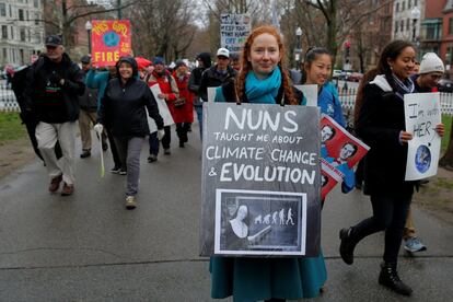 Una manifestante camina por la ciudad de Boston mientras sujeta una pancarta con el lema: 'Las monjas nos enseñaron acerca del cambio climático y la evolución humana'.