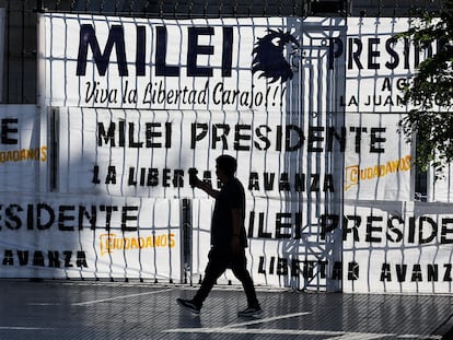 Un hombre camina fuera del Congreso argentino, cubierto por mantas a favor de Javier Milei, en Buenos Aires.