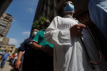 Varias personas con mascarilla hacen cola a las afueras de un colegio en el Cairo, durante la votación para las elecciones al Senado egipcio.