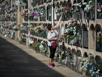 Una mujer deposita flores en un nicho del cementerio del Poblenou