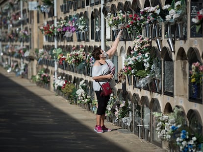 Una mujer deposita flores en un nicho del cementerio del Poblenou