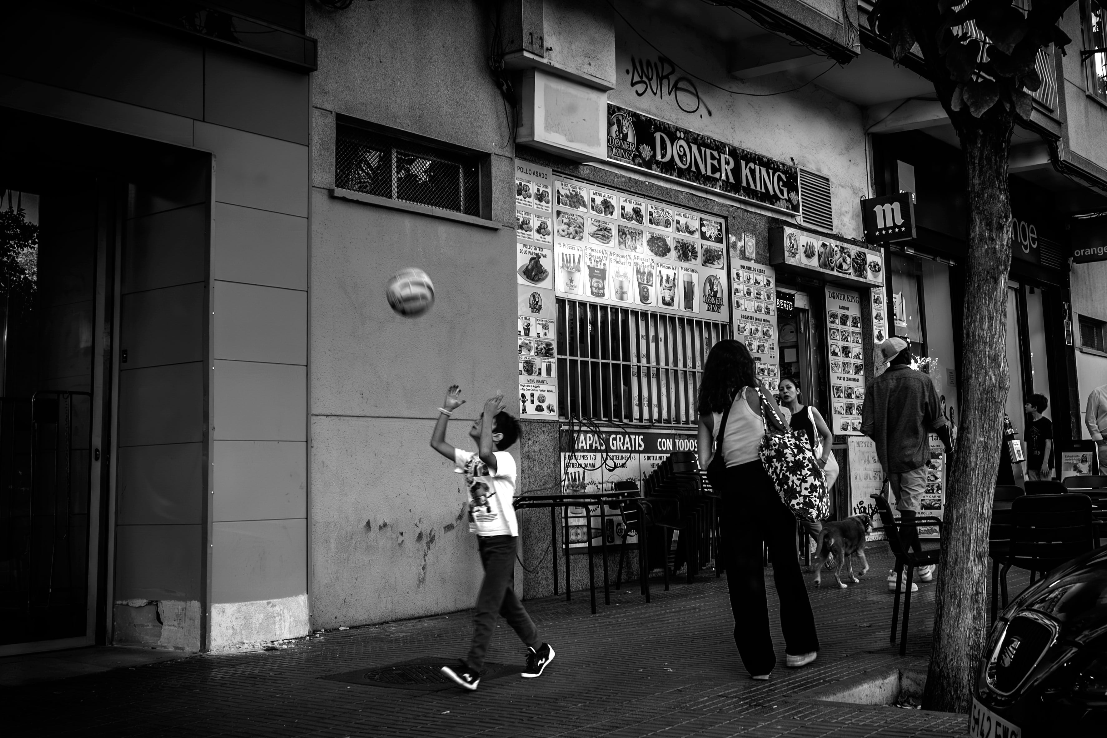 Un niño juega a la pelota en las calles de Madrid.