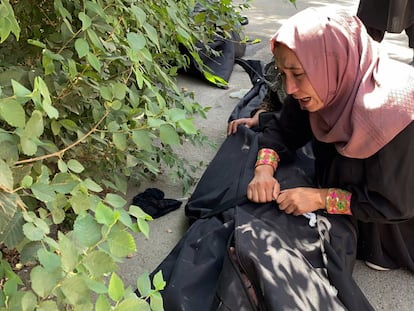 Mulher chora diante de um hospital de Cabul ao lado do corpo de uma vítima do atentado.