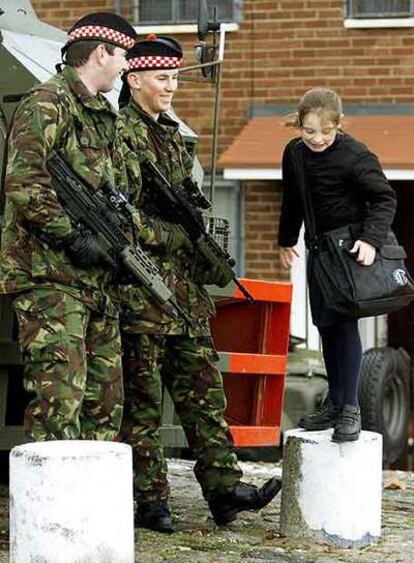 Un niña católica juega delante de dos soldados británicos en la zona norte de Belfast en noviembre de 2001.