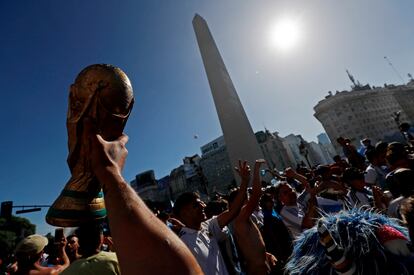 Un hincha levanta la Copa del Mundo frente al Obelisco, en Buenos Aires, este domingo tras la final.