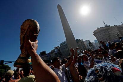 Un hincha levanta la Copa del Mundo frente al Obelisco, en Buenos Aires, este domingo tras la final.