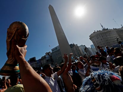 Un hincha levanta la Copa del Mundo frente al Obelisco, en Buenos Aires, este domingo tras la final.