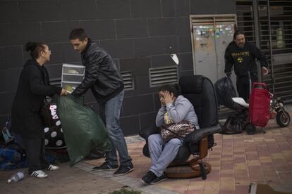 Verónica Labradas, sentada en una silla, mira como activistas y familiares retiran sus pertenencias de la calle tras ser desahuciada en Madrid (España).