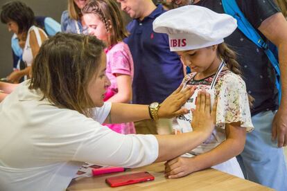 Una organizadora coloca una etiqueta sobre el delantal de una de las participantes al momento del registro del 'casting' de MasterChef Junior en Madrid.