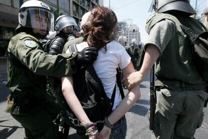 Los agentes detienen a una mujer en las calles de Atenas. Los antidisturbios han lanzado gases lacrimógenos contra los manifestantes.