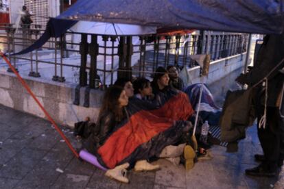 Protestors sit in the rain in Puerta del Sol after keeping vigil all Wednesday night despite a ban on demonstrating in the square.