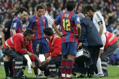 Los jugadores de los dos equipos observan a Eto'o en la camilla en la que abandonó lesionado el terreno de juego.