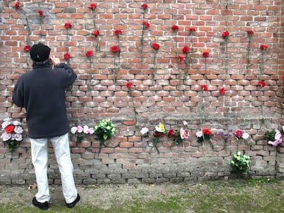 Un hombre pone claveles en las tapias del cementerio la Almudena de Madrid, en las que fueron fusiladas 2.663 personas.