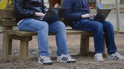 Dos jóvenes utilizan sus ordenadores en un parque de Sevilla.
