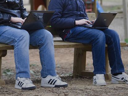 Dos jóvenes utilizan sus ordenadores en un parque de Sevilla.