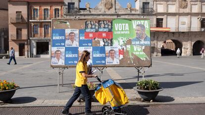 Elena Olivar pasa con su carro por delante de los carteles electorales ubicados en la Plaza Mayor de Medina del Campo.
